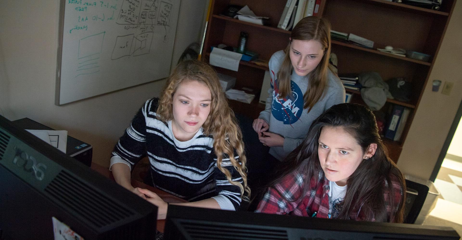 three students working on a computer